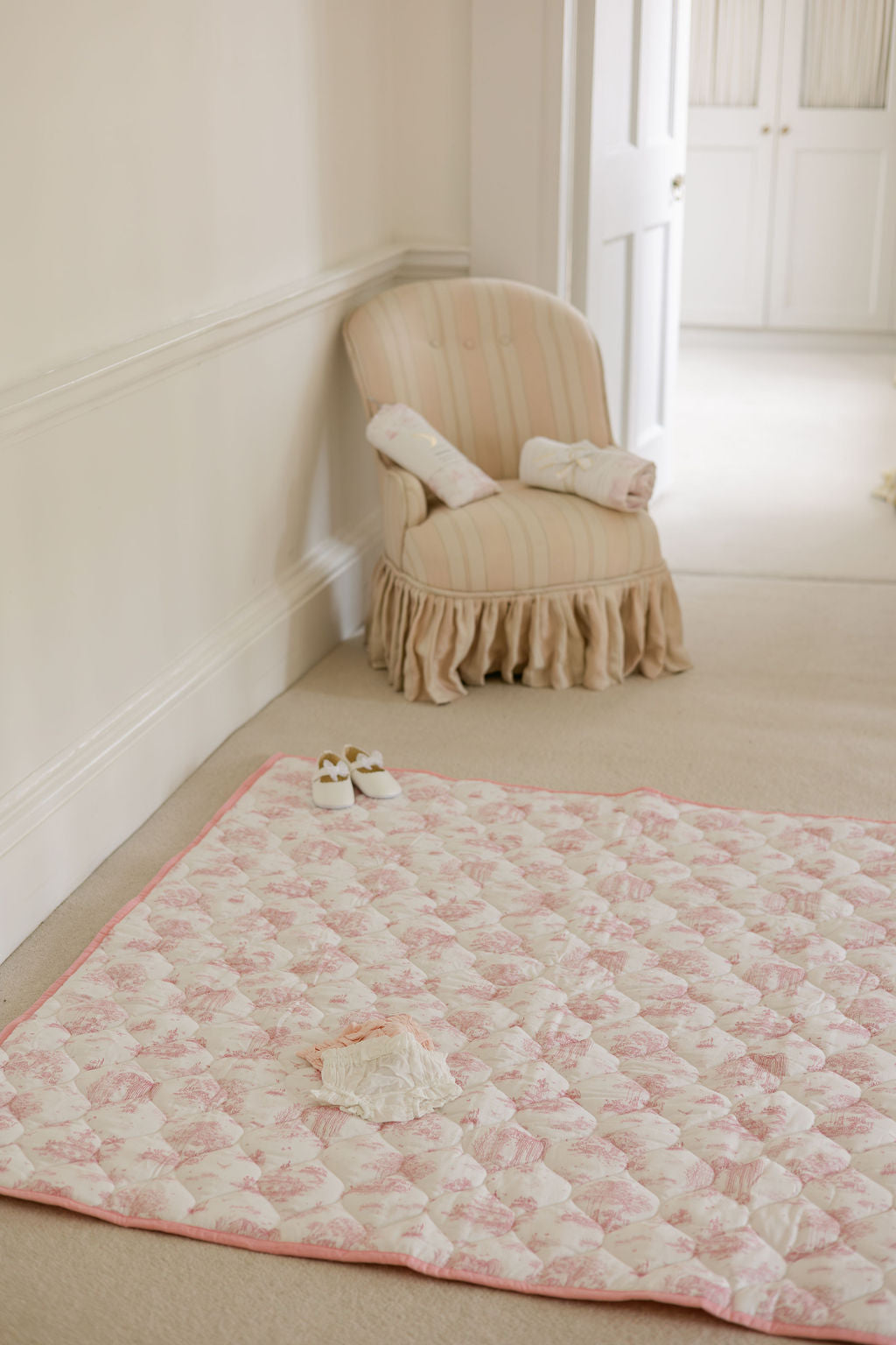 Spring Toile Pink quilted playmat spread on a nursery floor, showing its rectangular shape, toile print and pink border.