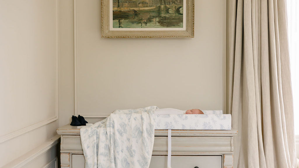 a baby lying on a change pad located on a antique dresser.
