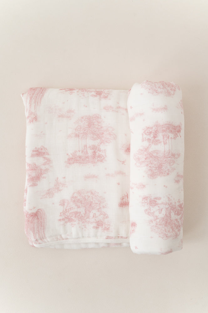 Spring Toile Pink bamboo baby blanket with one end rolled, showing pale pink pastoral scenes on cream fabric.